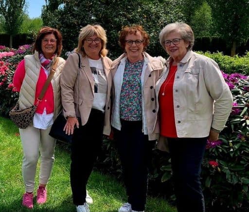 Vier lächelnde LandFrauen vor blühenden Büschen bei der Veranstaltung „Fashion erleben“.