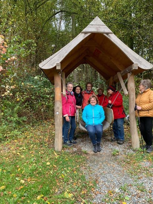 Wandergruppe der LandFrauen an einer überdachten Holzschaukel im Wald.