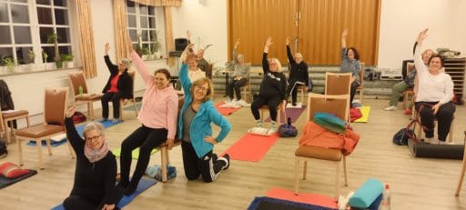 Landfrauen bei einer gemeinsamen Yogaübung auf Stühlen
