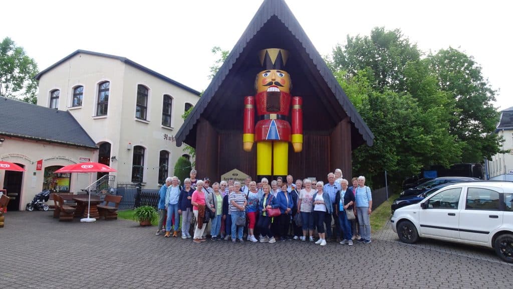 Reisegruppe vor einem großen Nussknacker in Seiffen